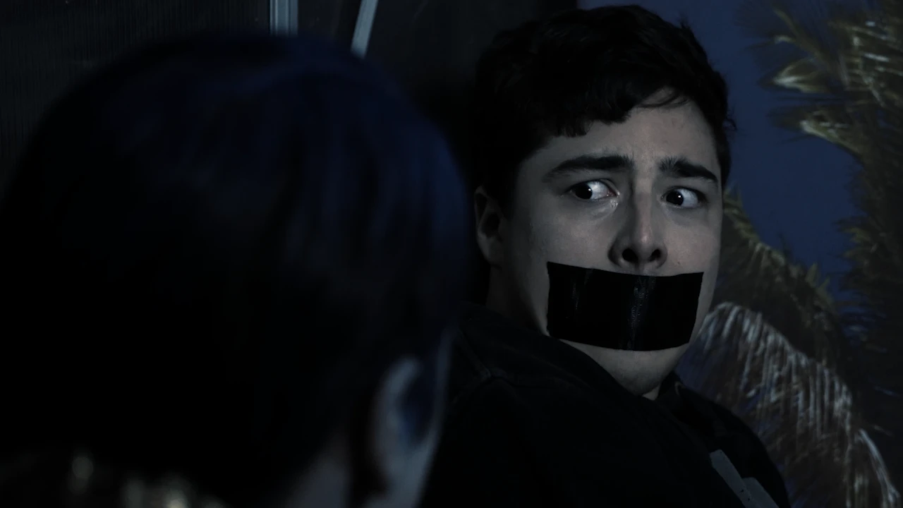 Ein junger Mann mit Klebeband über dem Mund blickt erschrocken zur Seite.
